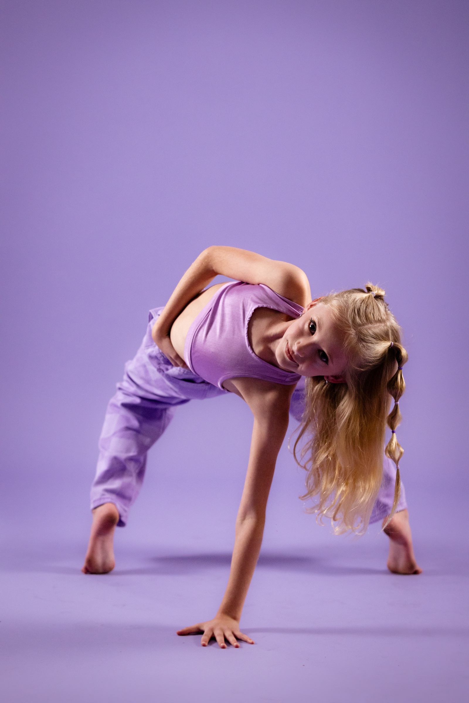 Young dancer moving low against a lilac studio background